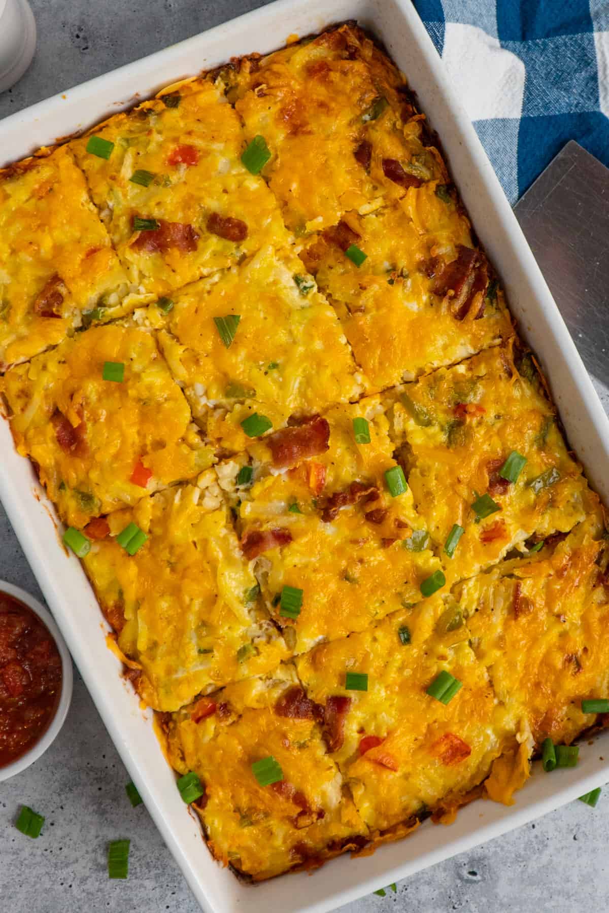 Overhead look at a hashbrown breakfast casserole sliced up in a white baking dish.