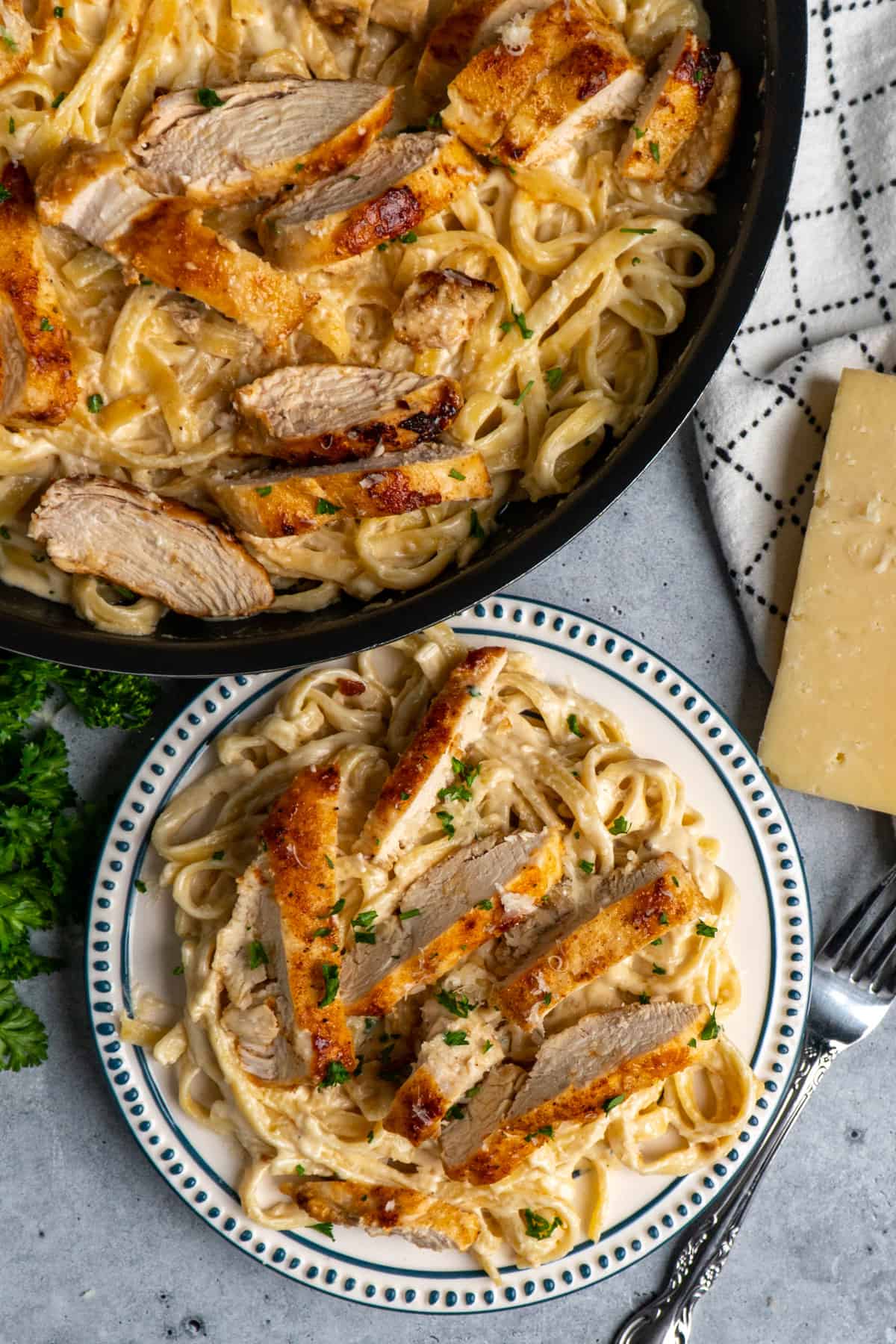 Chicken alfredo on a white plate and in a skillet.