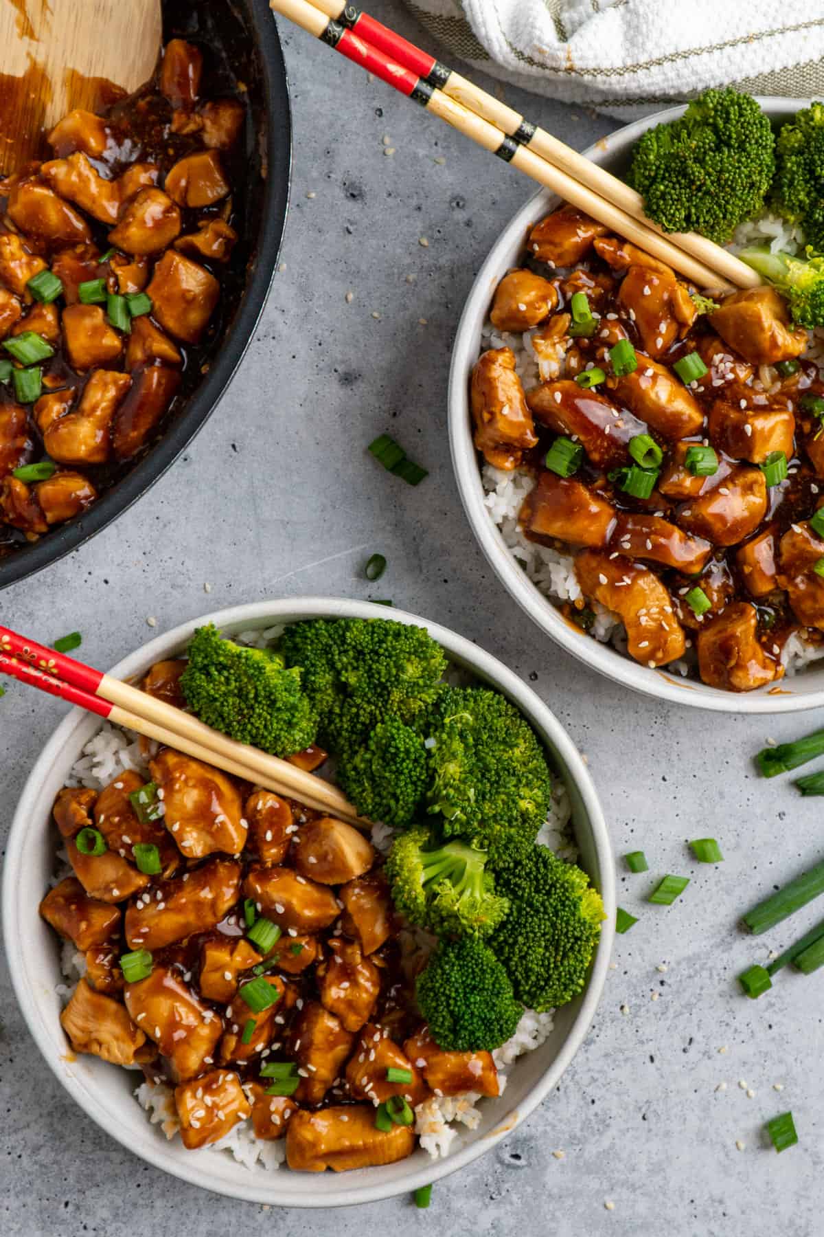 Overhead look at honey teriyaki chicken in two bowls over rice with broccoli