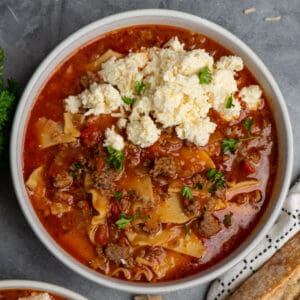 Easy lasagna soup in a bowl with ricotta cheese mixture on top and garnished with fresh parsley