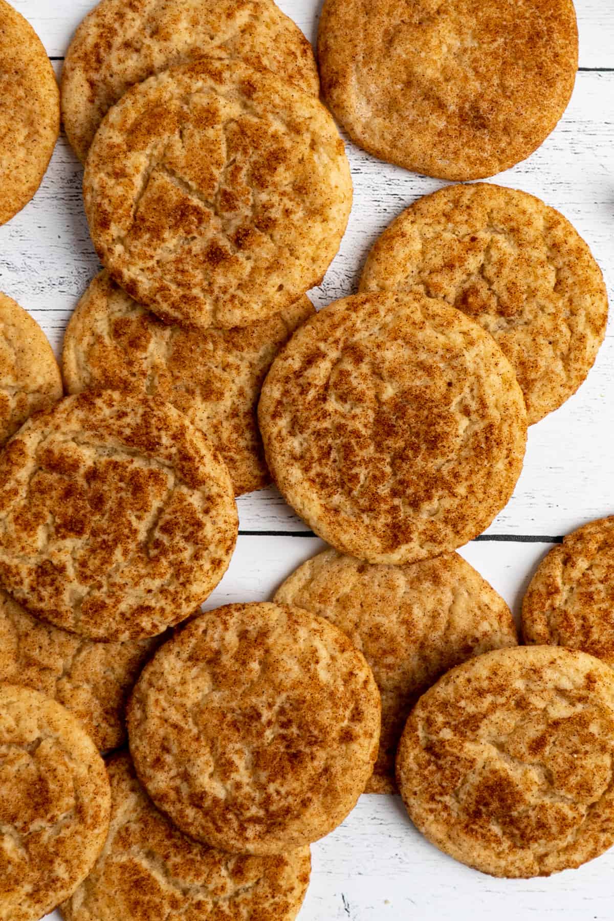 Snickerdoodles scattered out on a white wood background.