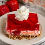 Strawberry pretzel salad on a white plate with whipped cream