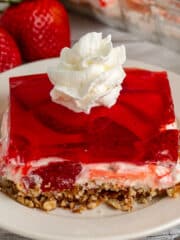 Strawberry pretzel salad on a white plate with whipped cream