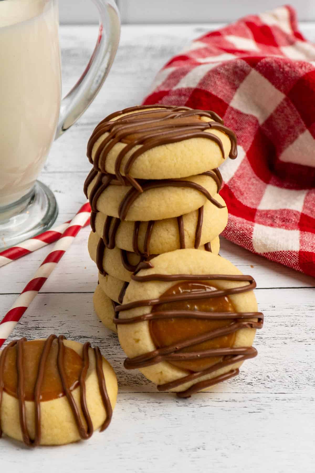 Cookies stacked up with a glass of milk in the background