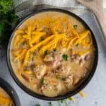 The Best Cheeseburger soup in a black bowl and garnished with cheddar cheese.