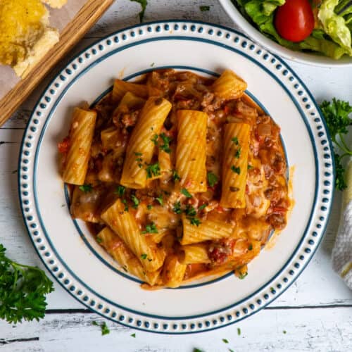 Overhead look at Instant Pot baked ziti on a plate with a salad in the background.