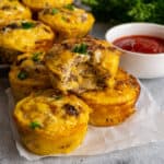 A sausage egg muffin with a bite taken out of it on top of more muffins.