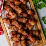 Bacon wrapped smokies on a wood cutting board.