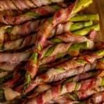 Close up of bacon wrapped asparagus on a wood cutting board.