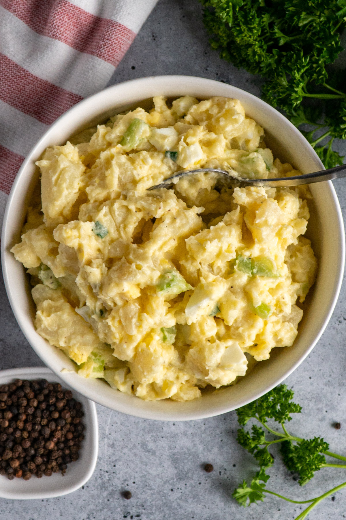 A spoon in a bowl of homemade potato salad.