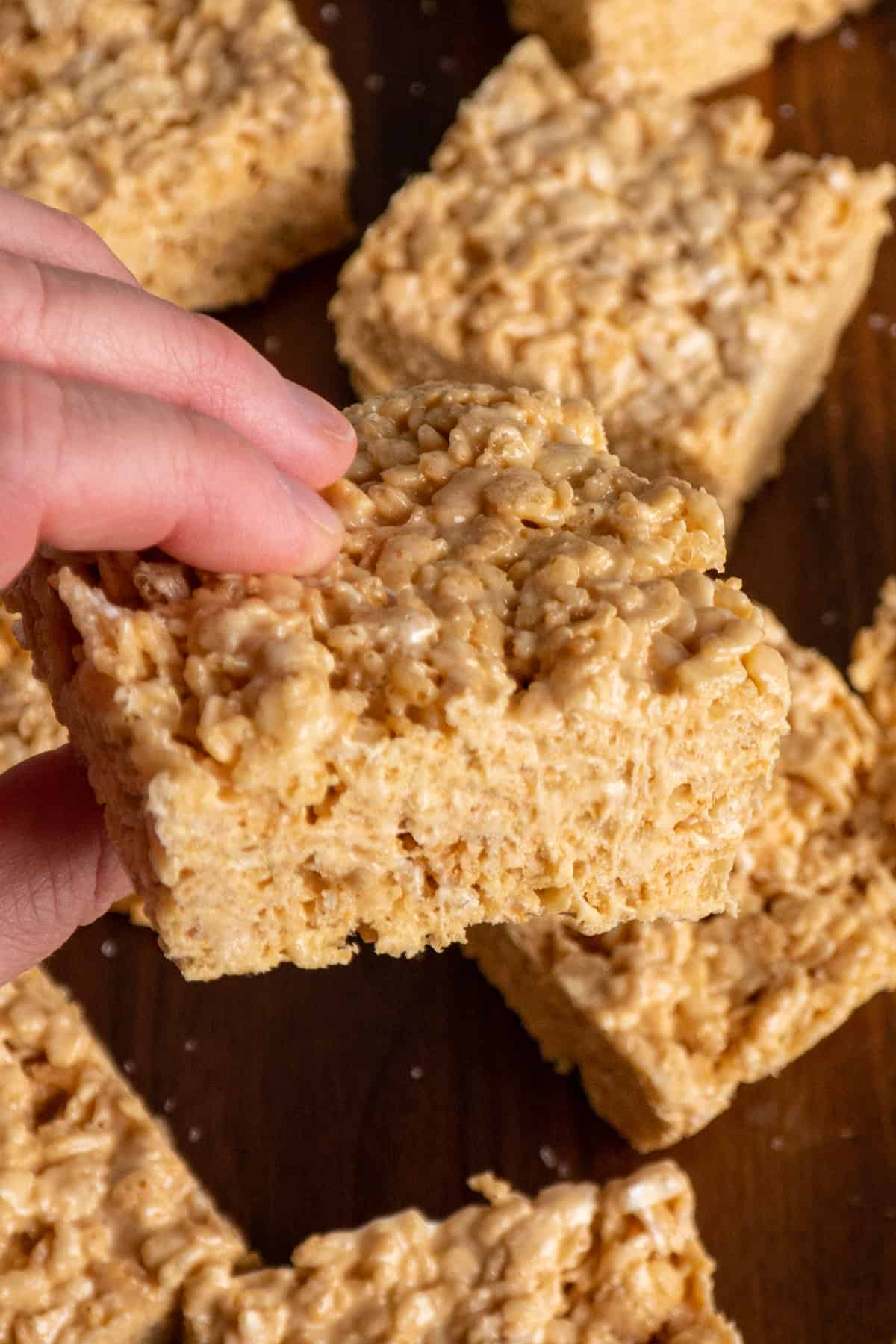 A hand holding a rice krispie treat.