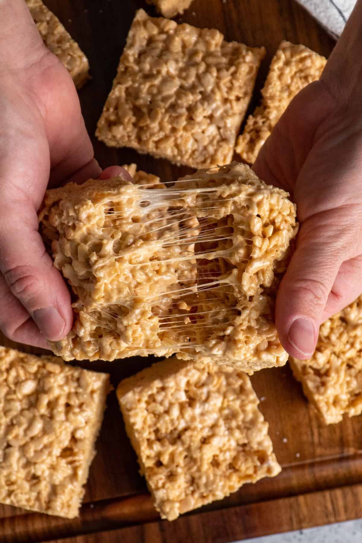 Two hands pulling apart salted caramel rice krispie treats.