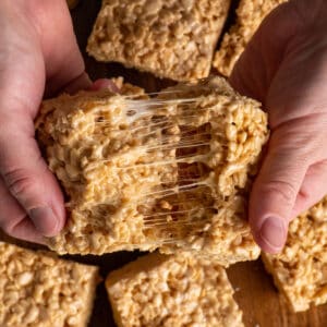 Two hands pulling apart salted caramel rice krispie treats.