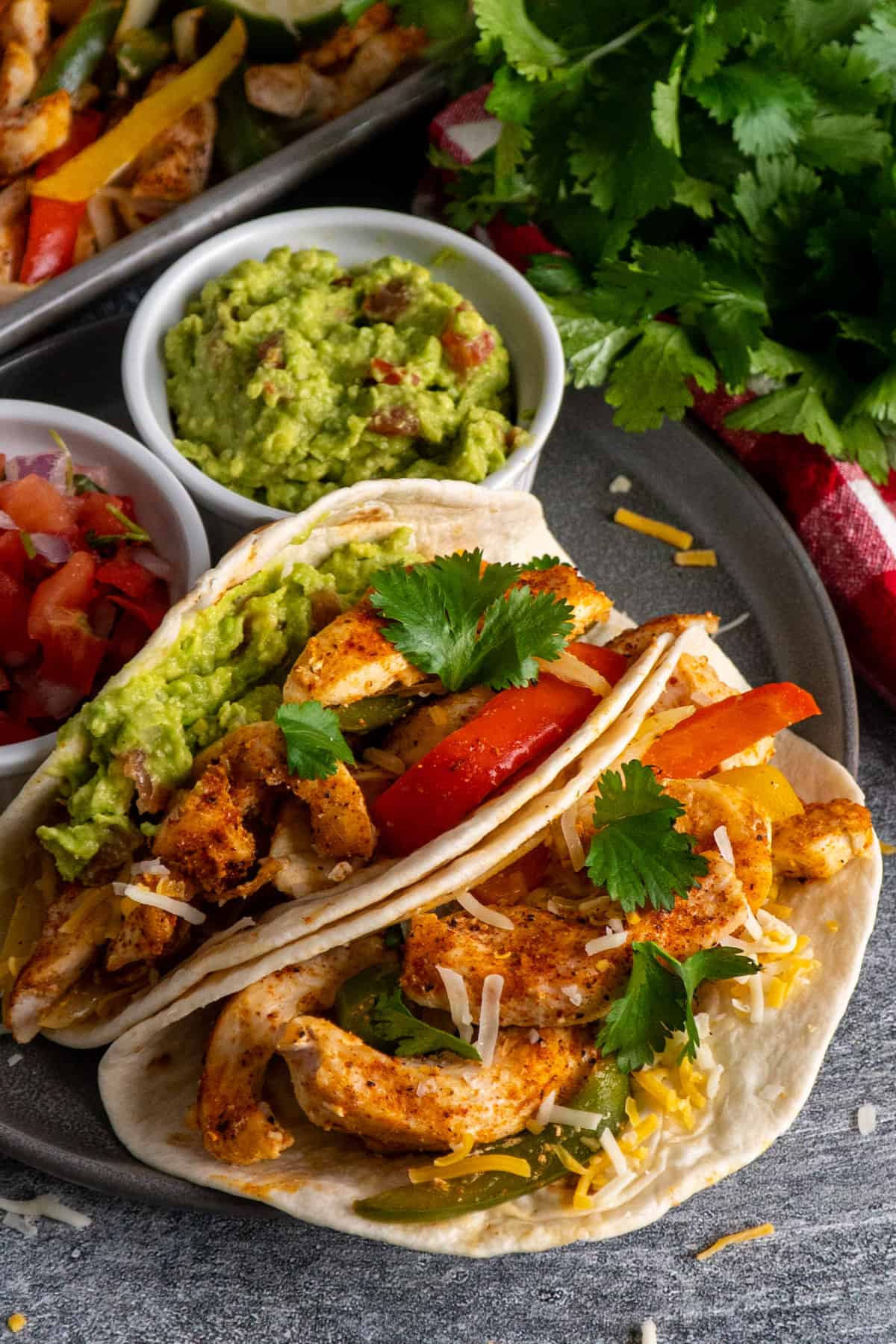 Close up of chicken fajitas garnished with guacamole, cheese and cilantro.