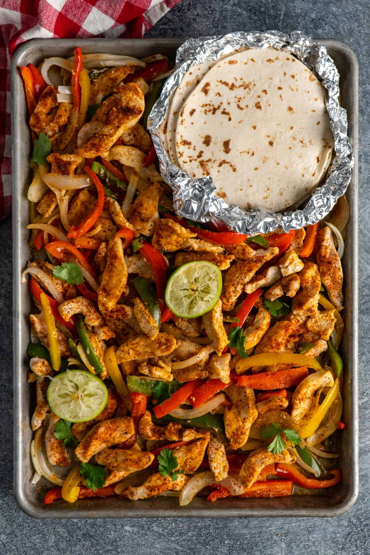 Sheet Pan chicken fajitas with fresh squeezed limes and tortillas.