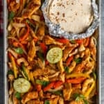 Sheet pan chicken fajitas with fresh squeezed limes and tortillas.