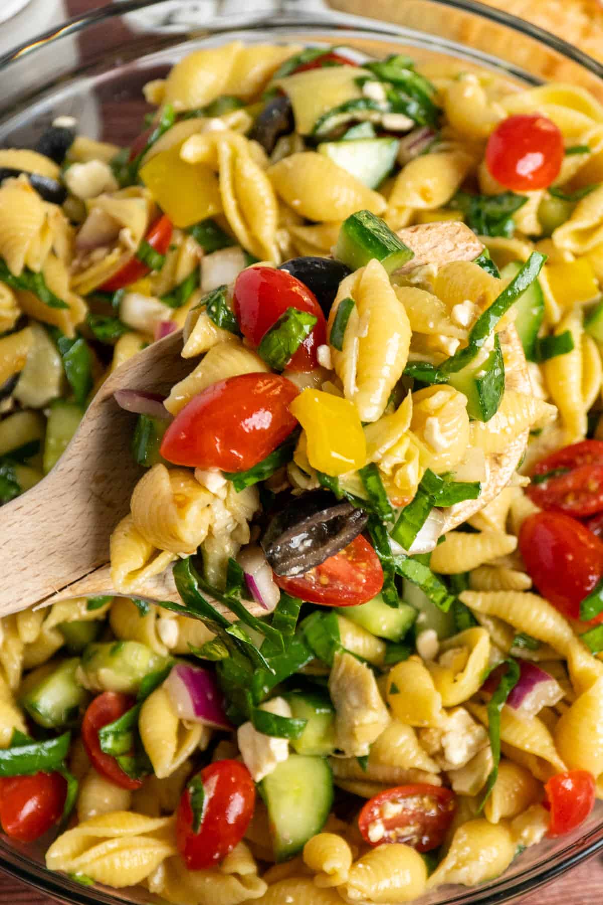 A wooden spoon holding pasta salad.