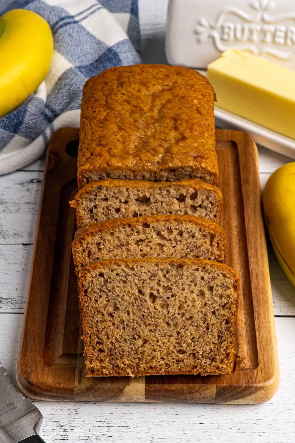 Banana bread on a wood cutting board with three slices cut off.