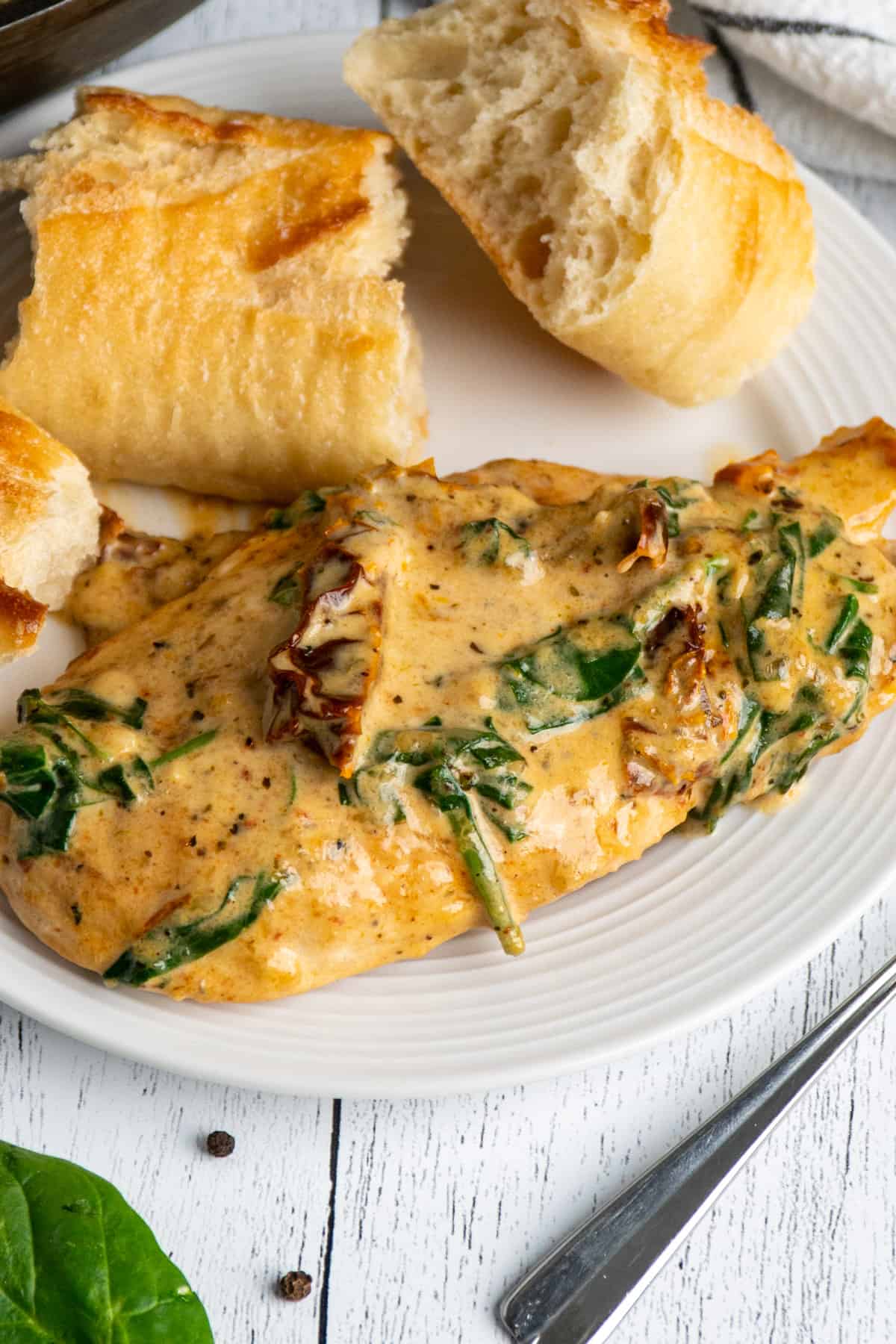 Tuscan chicken on a plate with bread.
