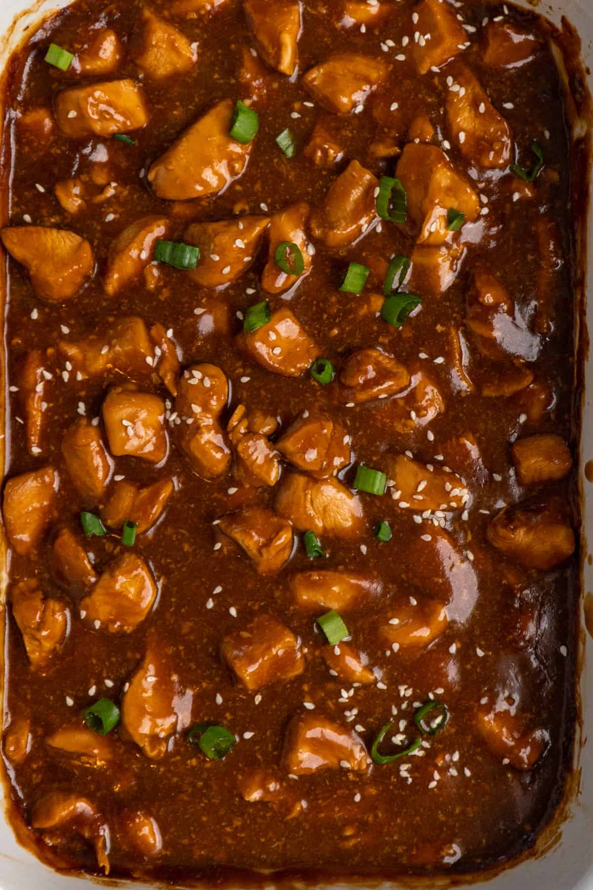 Teriyaki chicken in a slow cooker garnished with green onions.