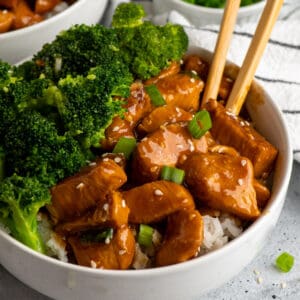 Slow cooker teriyaki chicken over a bowl of rice with broccoli.
