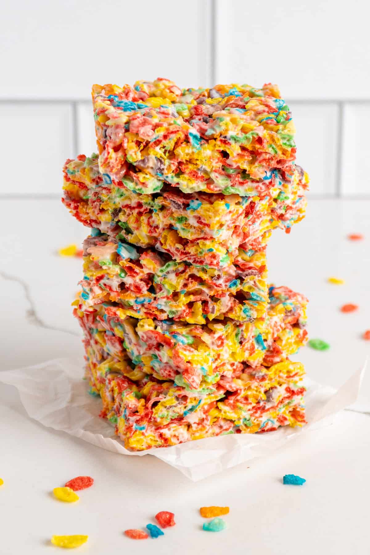 Five fruity pebbles rice crispy treast stacked on top of each other with a white background.