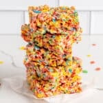 Five fruity pebbles rice crispy treasts stacked on top of each other with a white background.