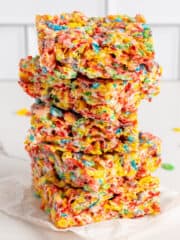Five fruity pebbles rice crispy treast stacked on top of each other with a white background.