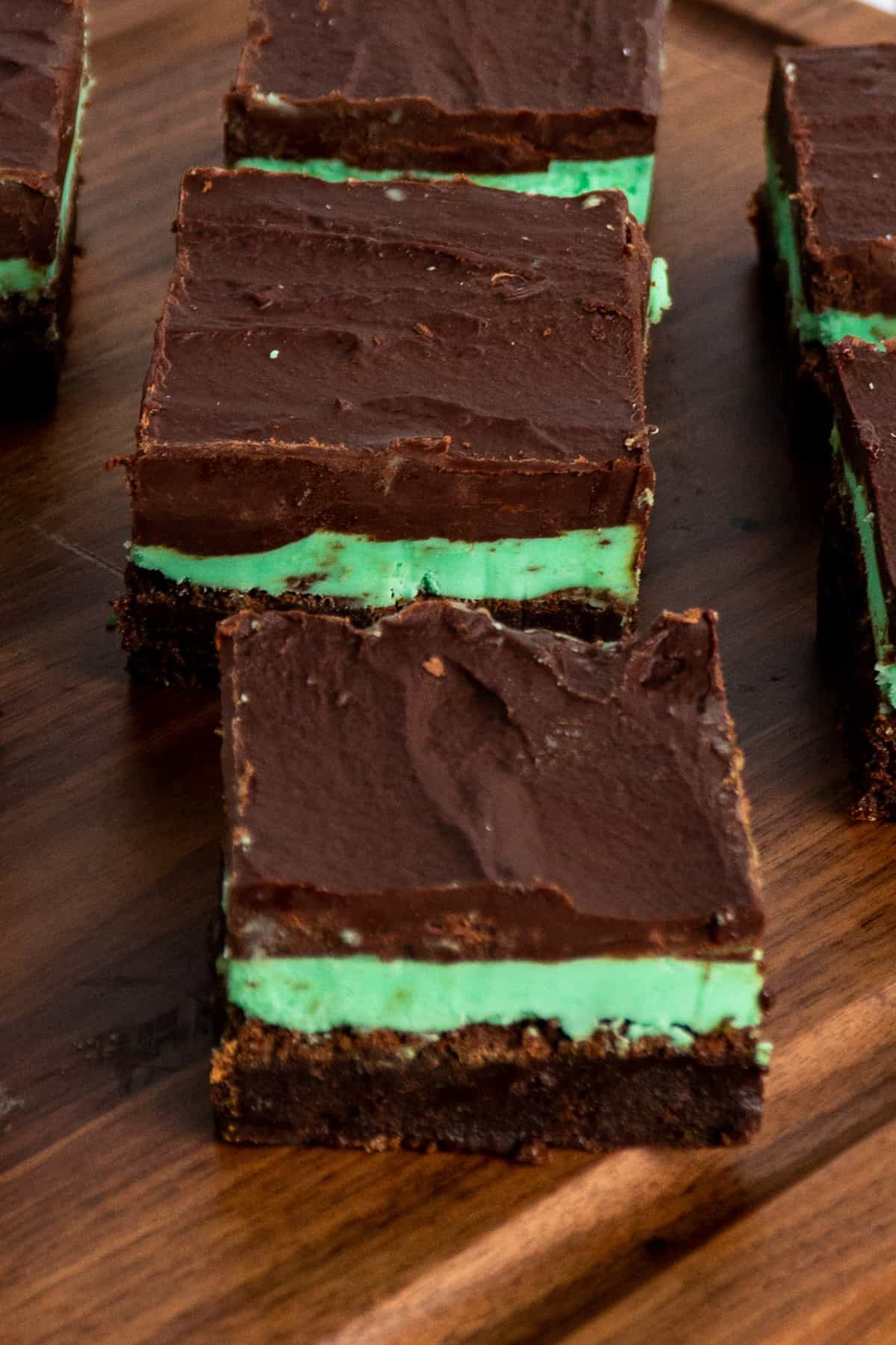 Close up of mint chocolate brownies on a wood cutting board.