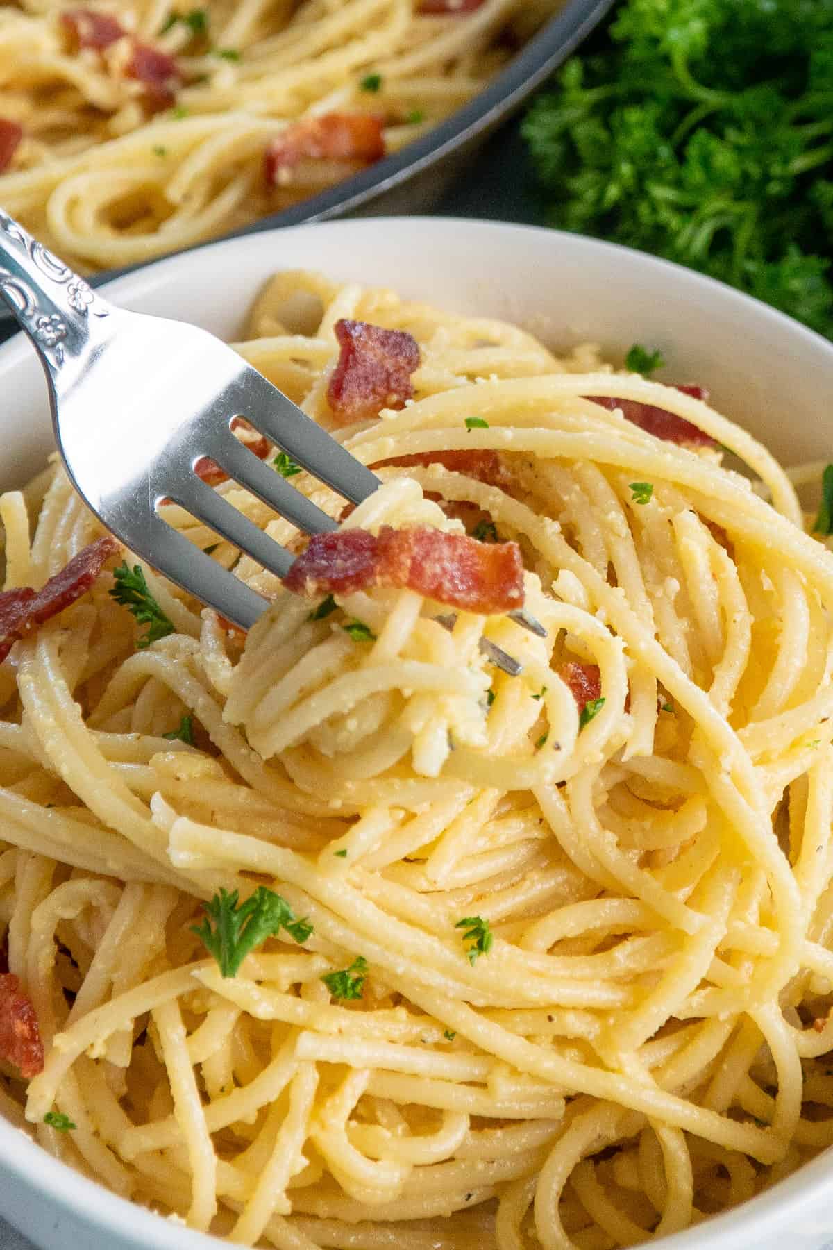 A fork with a bite of spaghetti carbonara.