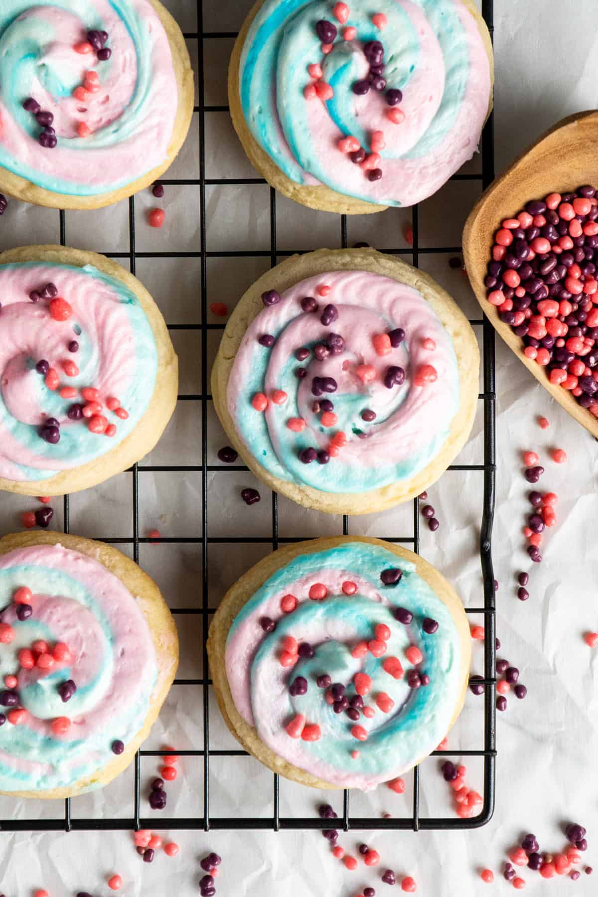Cotton candy Crumbl cookies on a a black cooling rack.
