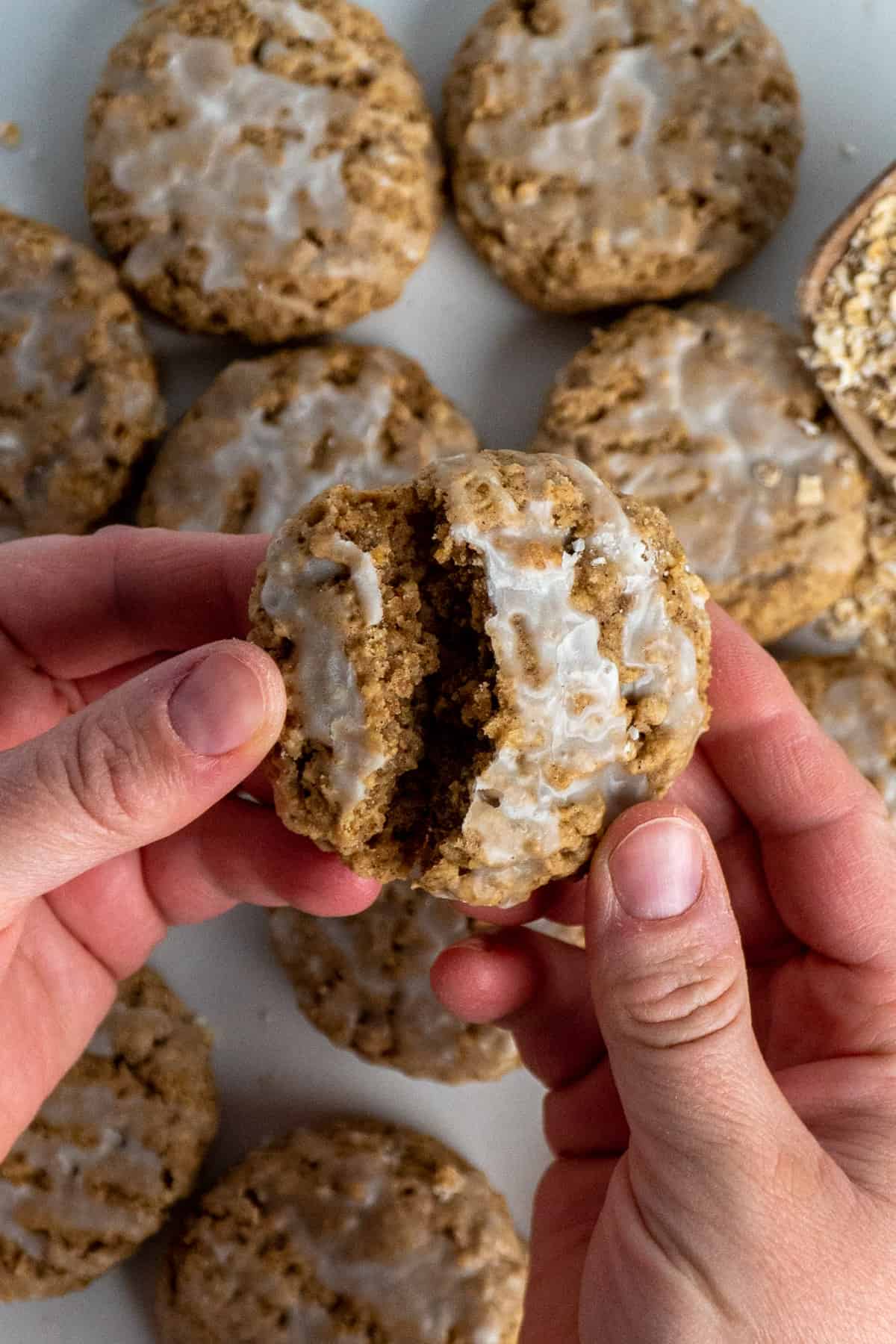 Hands breaking an oatmeal cookie in half.