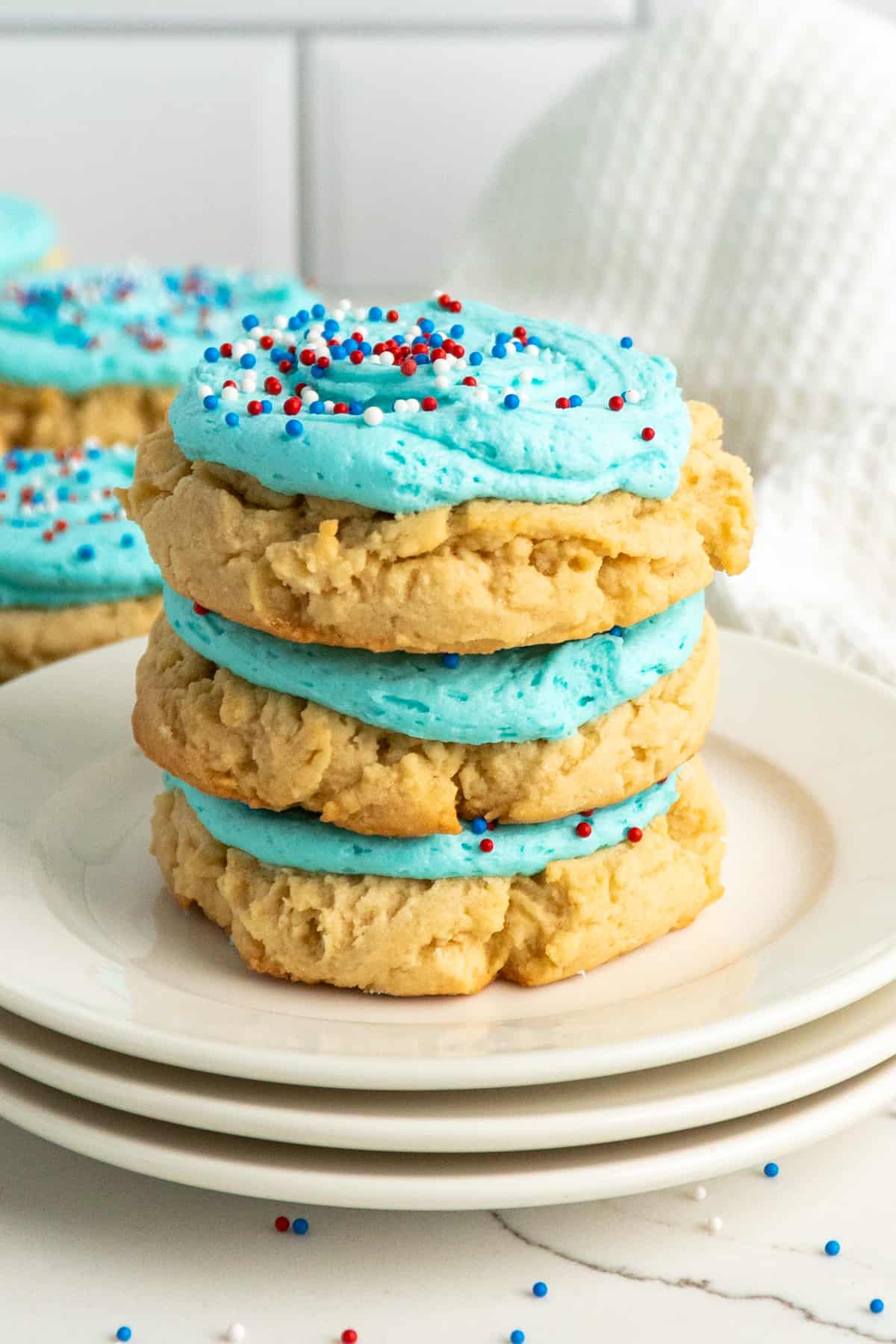 Three frosted sugar cookies stacked on top of each other.