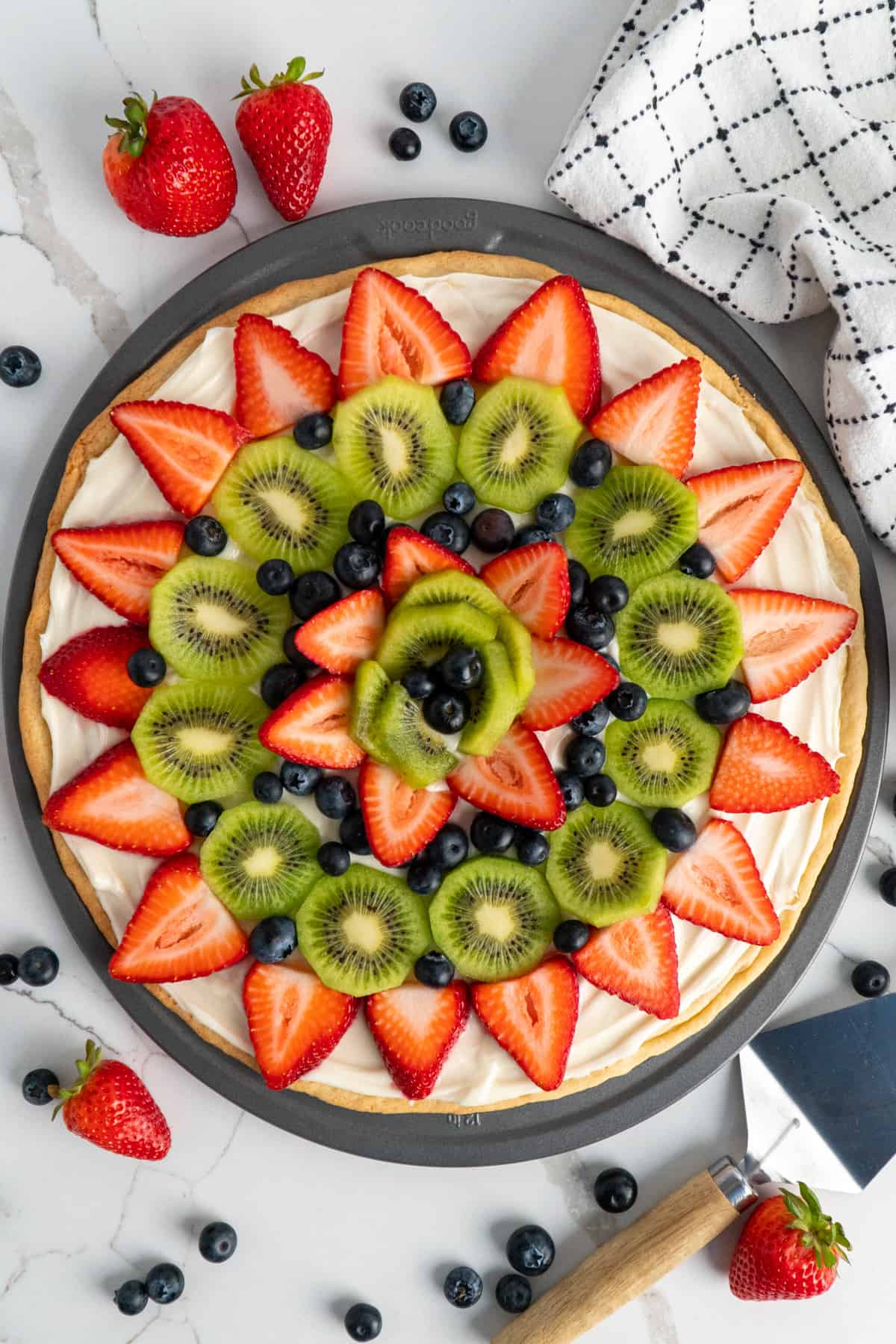 Overhead, look at fruit pizza on a pizza pan.