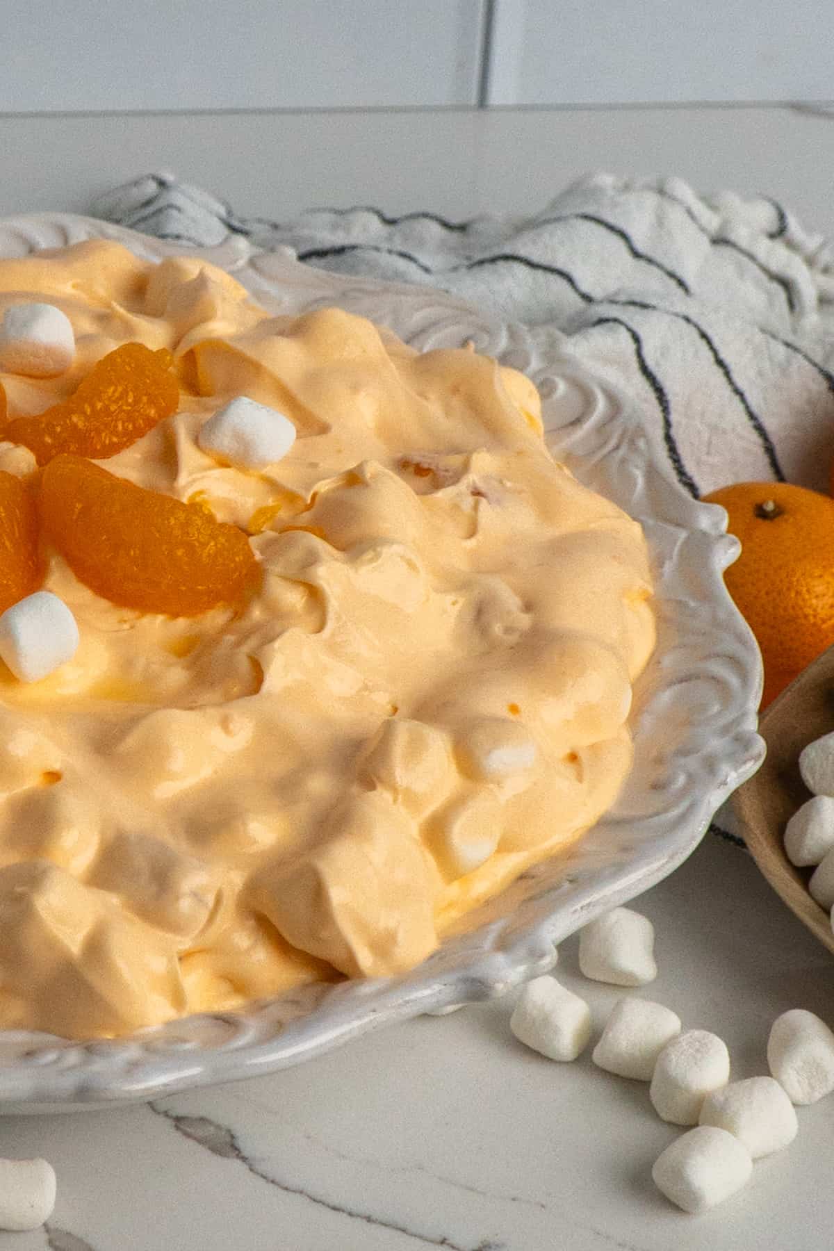 Orange fluff salad topped with mandarin oranges and marshmallows.
