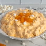 Orange fluff salad topped with mandarin oranges and marshmallows.