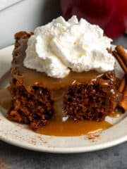 Close-up of caramel apple cake on a plate topped with whipped cream.