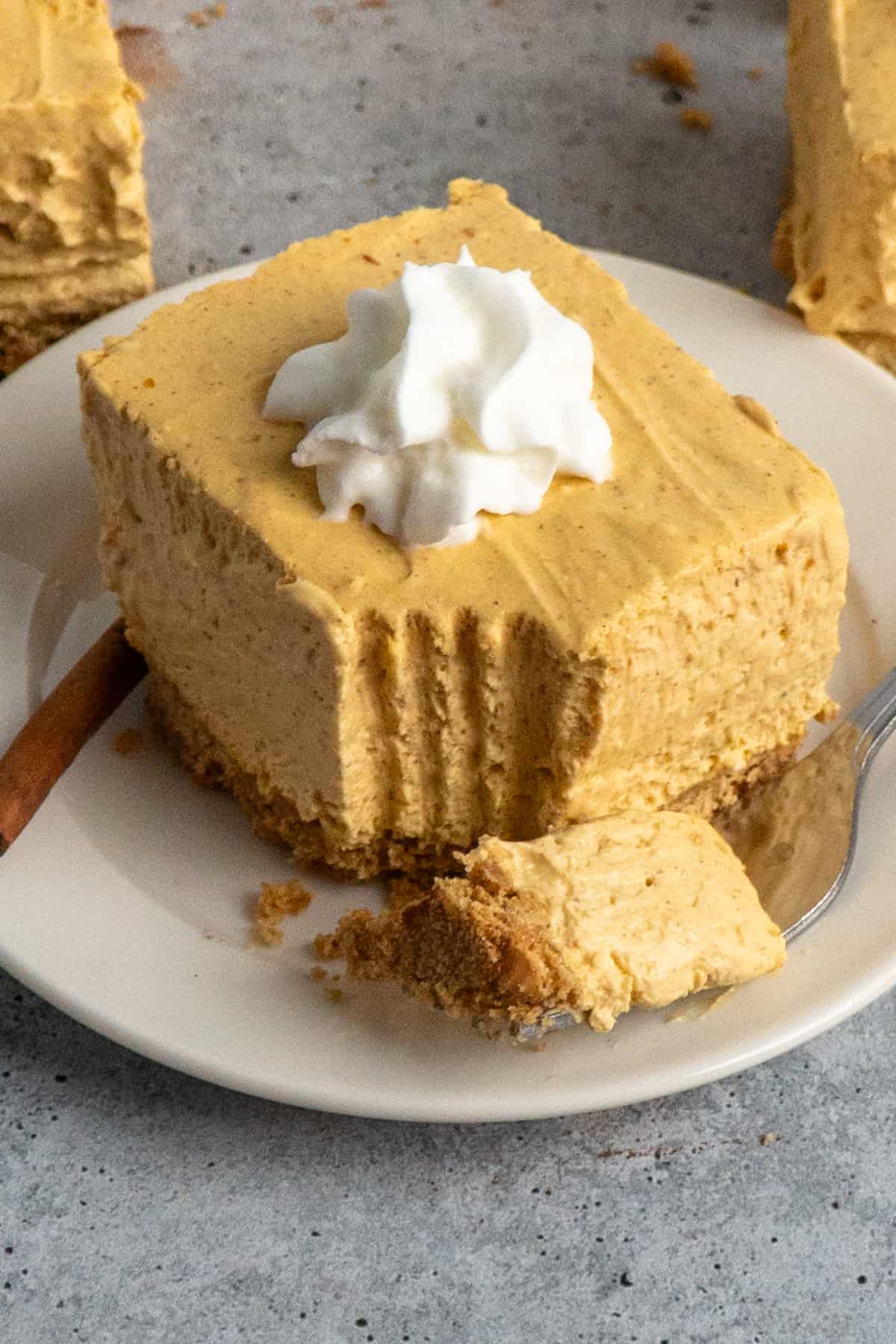 Close-up of a no-bake pumpkin cheesecake bars on a plate with a bite taken out.