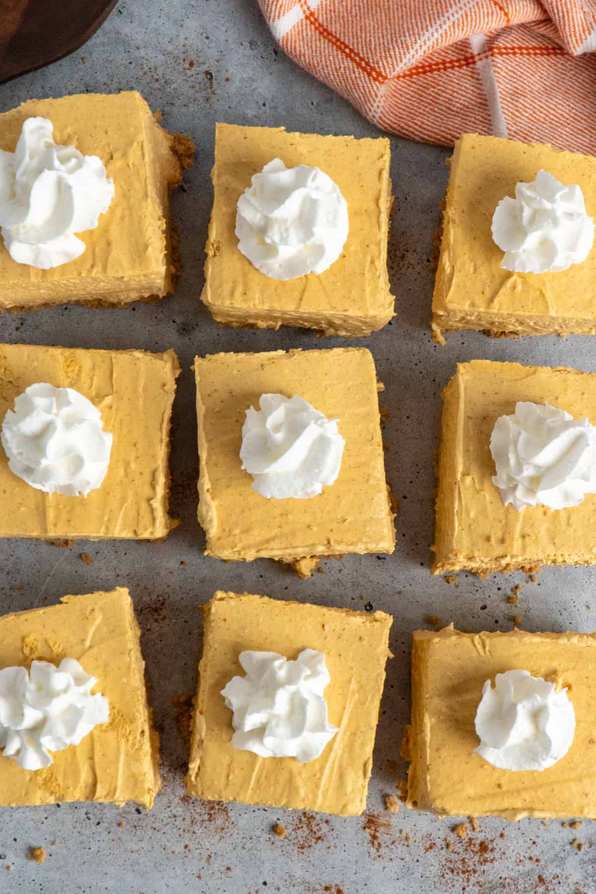 Overhead look at no-bake pumpkin cheesecake bars on a gray background.