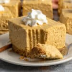Close-up of a no-bake pumpkin cheesecake bars on a plate with whipped cream on top.