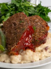 Close up of the best meatloaf recipe on garlic mashed potatoes.