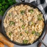 Overhead look at chicken Alfredo with broccoli in a skillet.