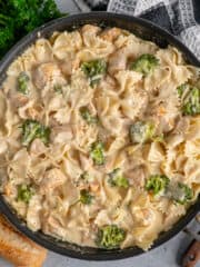 Overhead look at chicken Alfredo with broccoli in a skillet.