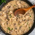 A wooden spoon in a skillet with chicken stroganoff.