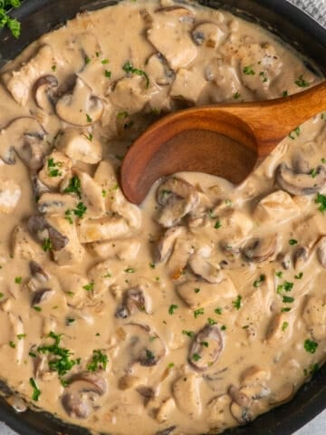 A wooden spoon in a skillet with chicken stroganoff.
