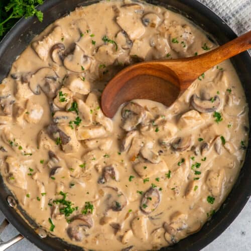 A wooden spoon in a skillet with chicken stroganoff.