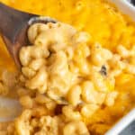 Close-up of a wooden spoon holding a scoop of homemade baked mac and cheese.