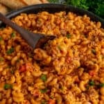 Close up of a wooden spoon scooping hamburger helper lasagna.