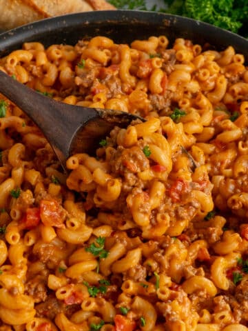 Close up of a wooden spoon scooping hamburger helper lasagna.