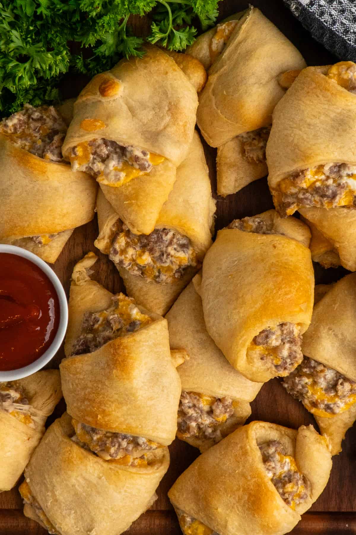 Overhead look at sausage cream cheese crescent rolls on a wood cutting board.